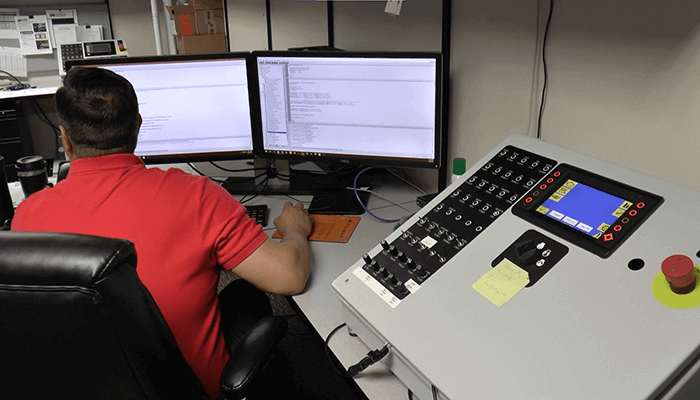 Controls-Programmer-Small A man working at a computer to program equipment controls