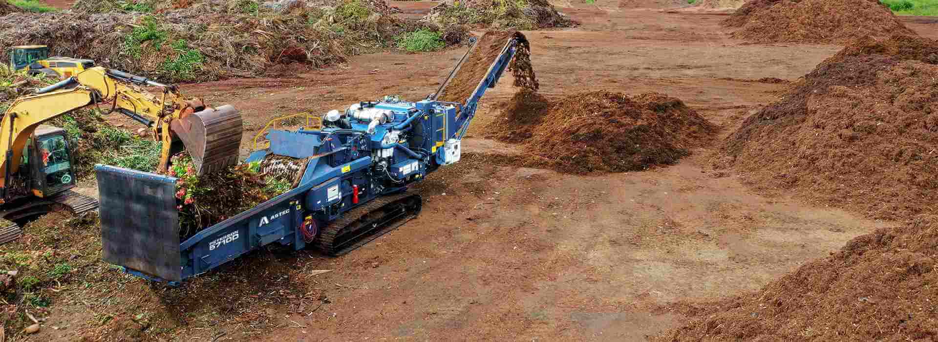 Astec Peterson 5710D Horizontal Grinder making compost from green waste in Hawaii with an loading excavator.